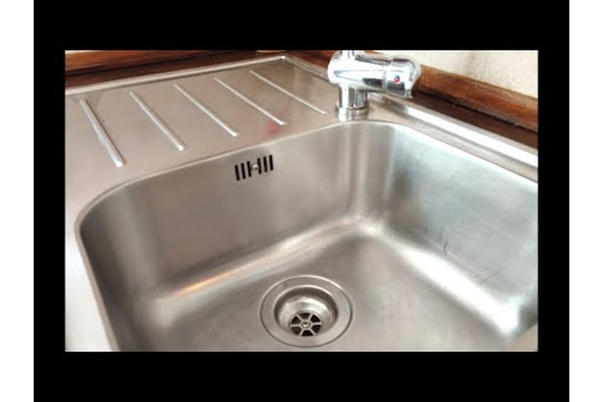 Lavello in acciaio inox lucido con riflessi di luce.