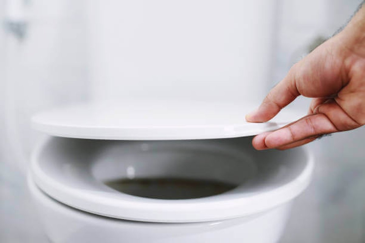 Uomo che pulisce il copriwater con un detergente e un panno.